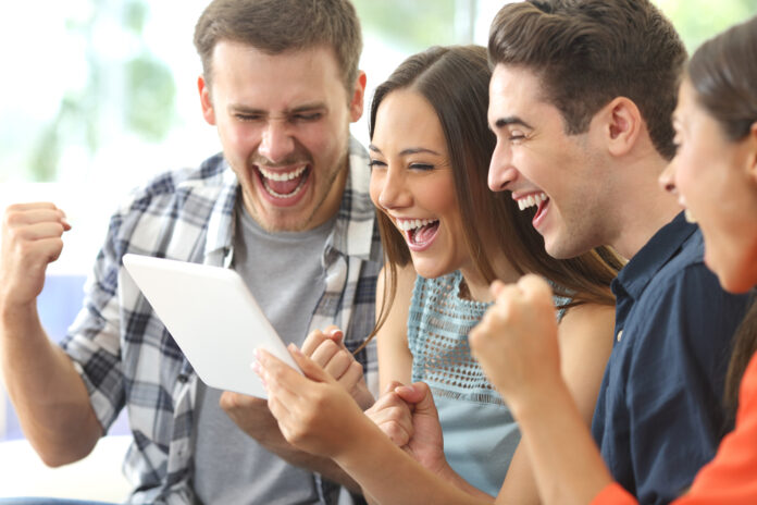 Excited,Group,Of,Four,Friends,Viewing,Media,Content,On,Line